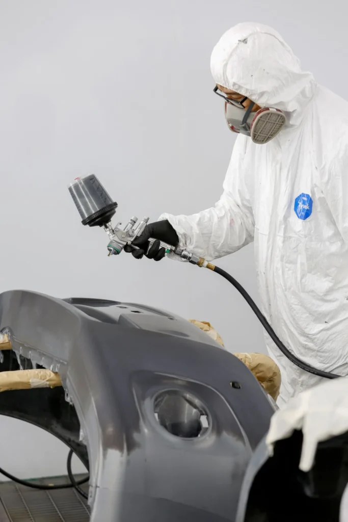 Technician spray painting a bumper during paint chip repair in Markham