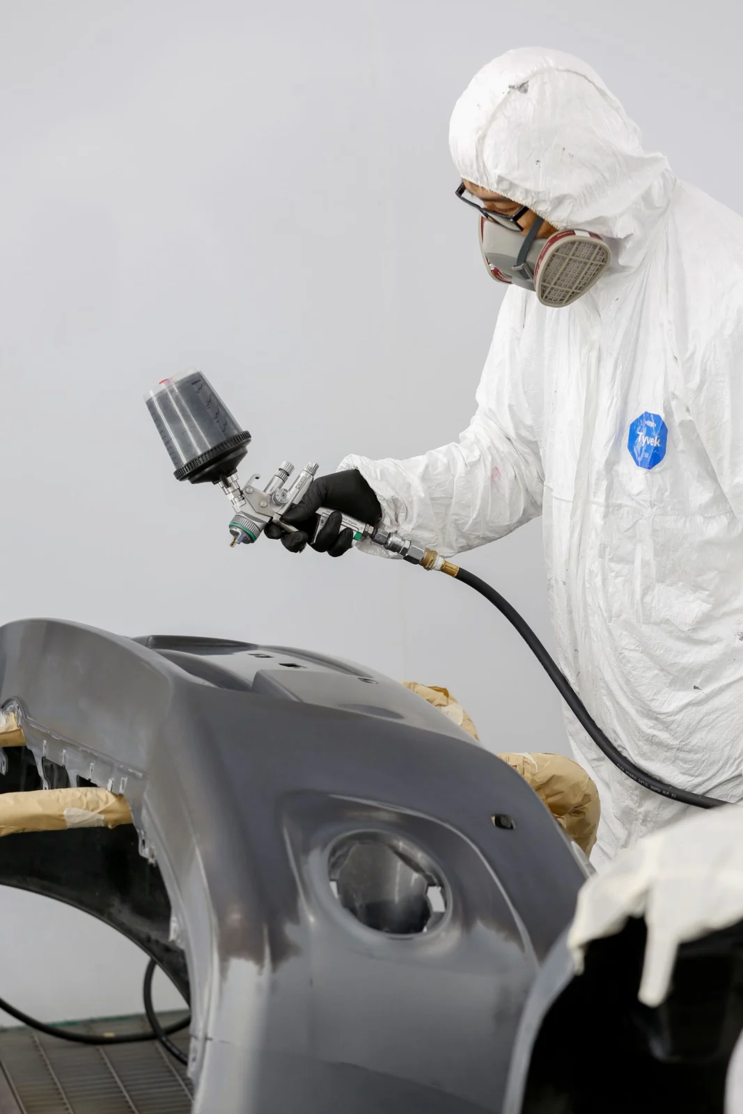 Technician spray painting a bumper during paint chip repair in Markham